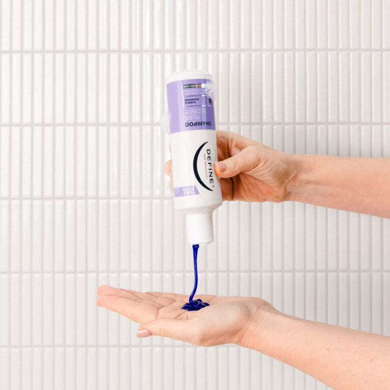 lillashampoo sprutes i en hånd foran hvite fliser