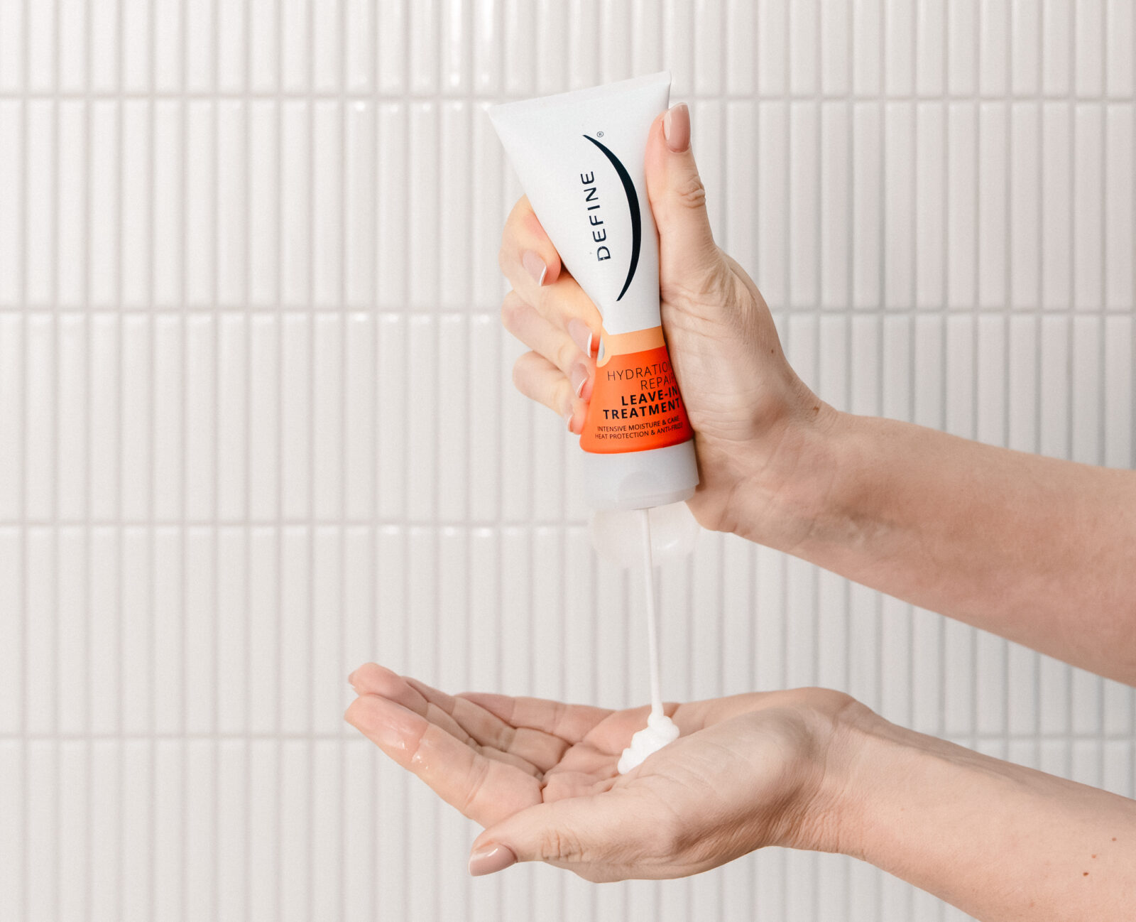 Hånd som klemmer en tube med leave-in og priduktet havner i hånden under