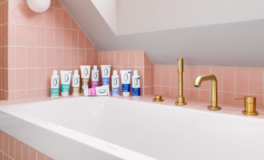 alle shampoo og balsam fra define står samlet på en badekarskant foran rosa fliser