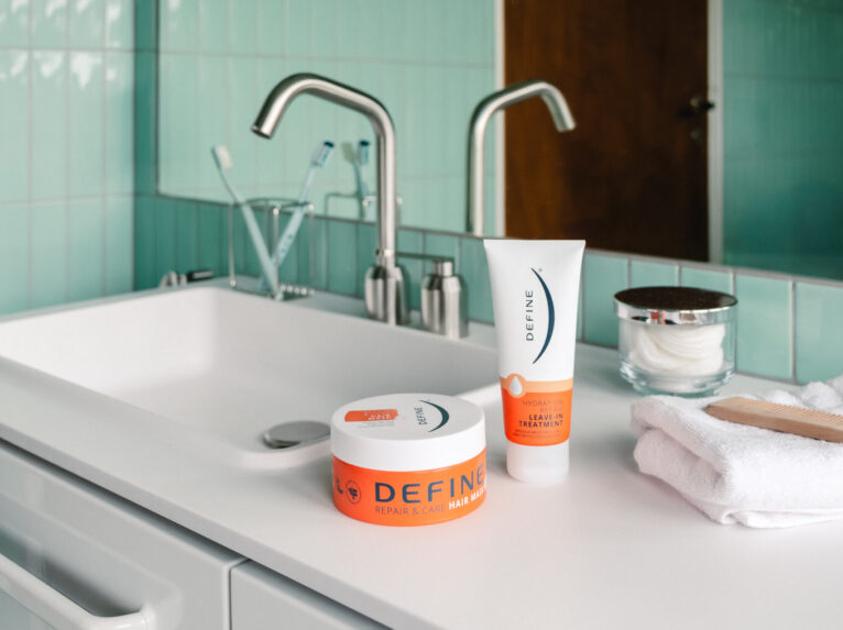 Hårkur og leave-in står på vasken i et turkis bad