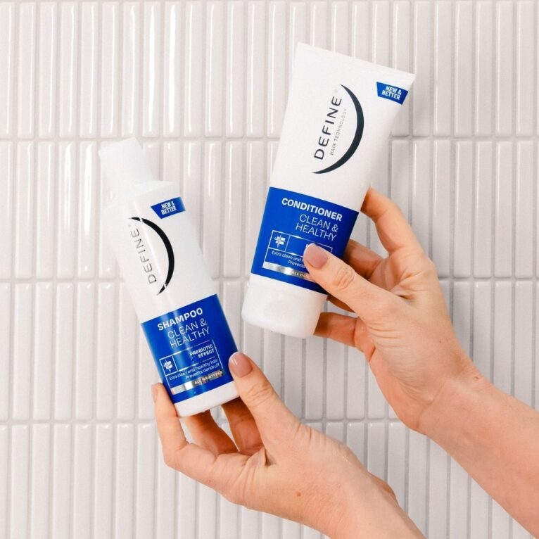to hender som holder opp shampoo og balsam fra define clean & healthy foran hvit flisvegg