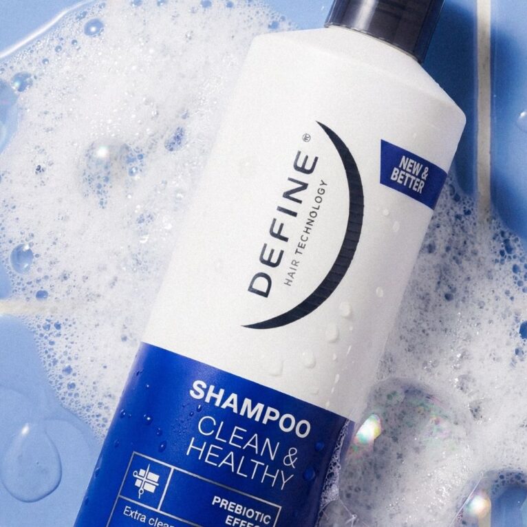 Shampooflaske på blå fliser omringet av skum